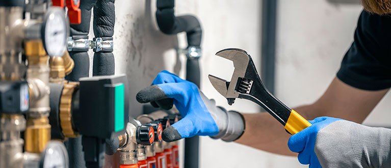 man-installs-heating-system-house-checks-pipes-with-wrench
